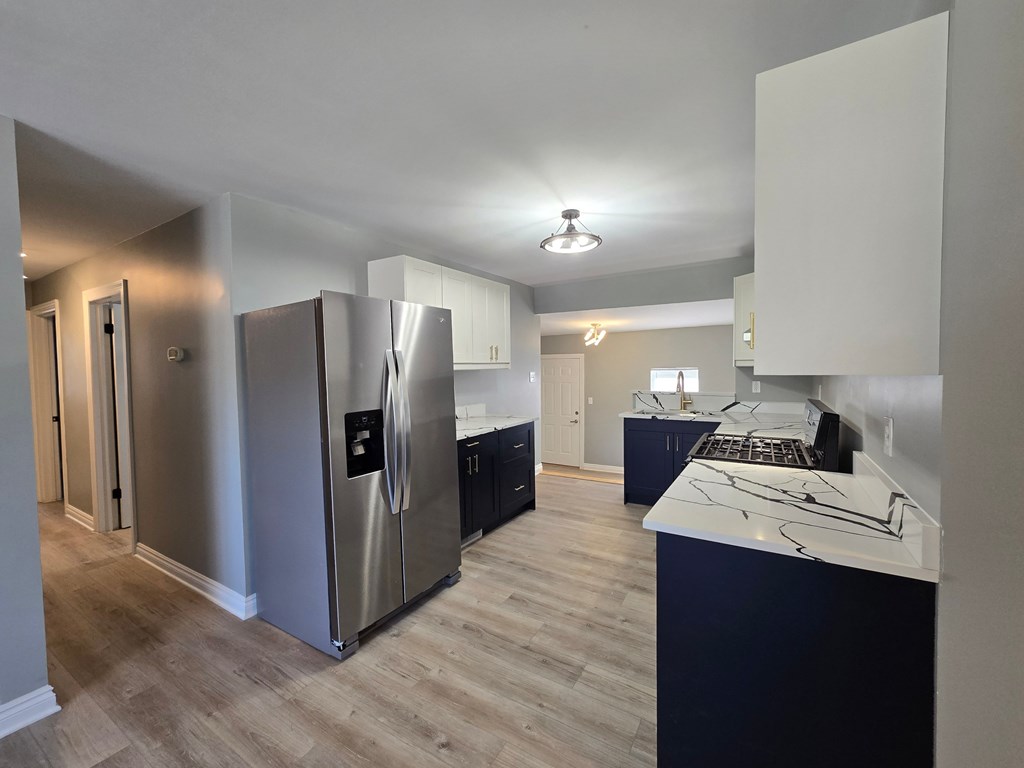 A kitchen with a stainless steel refrigerator and a white counter top.