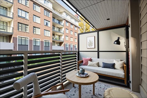 A balcony with a table and chairs overlooks a brick building.
