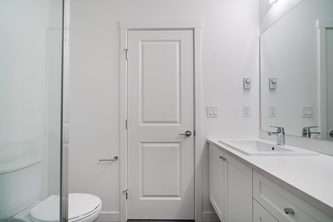 A white bathroom with a toilet, sink, and mirror.