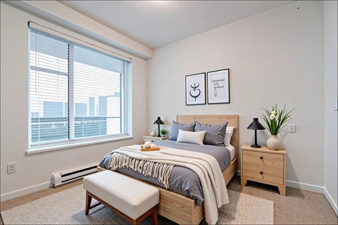 A bedroom with a large bed, a bench, and two nightstands.