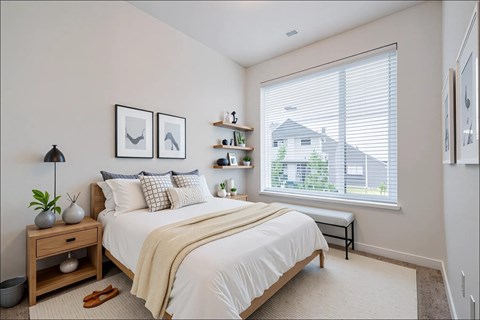 A bedroom with a large bed and a window with blinds.