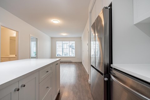 A modern kitchen with a stainless steel refrigerator and white countertops.