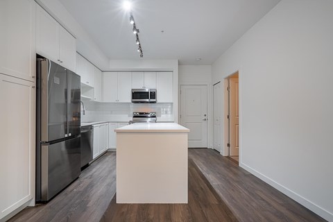 A kitchen with a refrigerator, microwave, and oven.