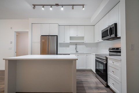 A kitchen with a white color scheme and a large island.