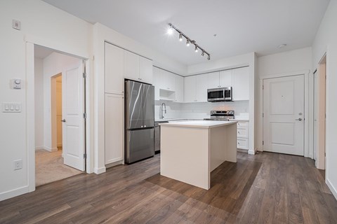 A kitchen with a refrigerator, microwave, and oven.