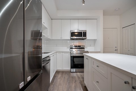 A modern kitchen with a stainless steel refrigerator and white cabinets.