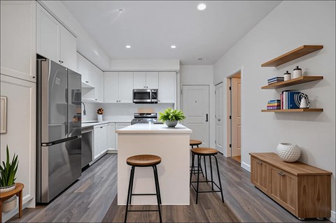 A modern kitchen with a white island and stools.