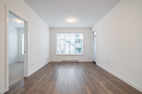 A room with wooden floors and a window with blinds.