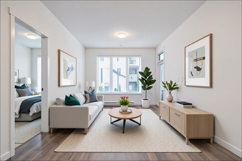 A living room with a grey couch, a coffee table, and a large window.