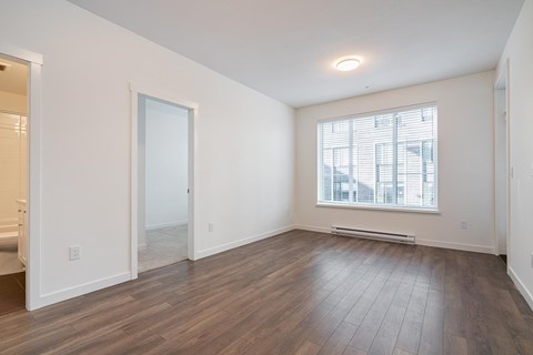 A room with wooden floors and a window with blinds.