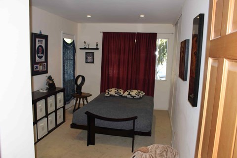 A bedroom with a bed, chair, and pictures on the wall.