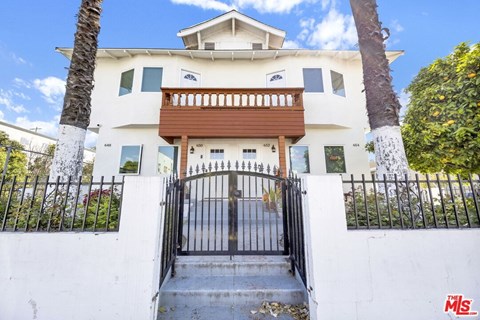 A white house with a black gate in front.