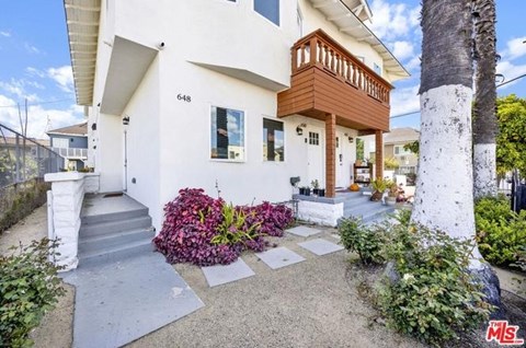 A white house with a brown balcony and a number 648 on the wall.
