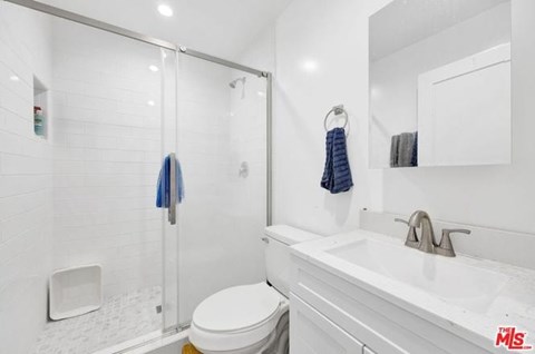 A white bathroom with a toilet, sink, and shower.