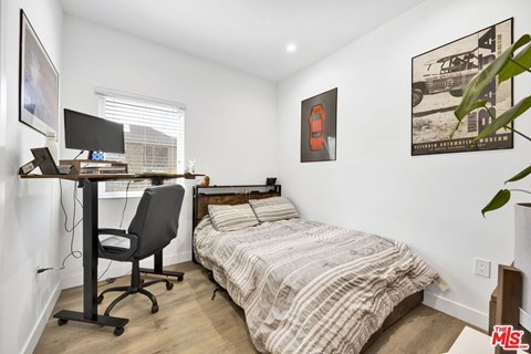 A bedroom with a bed, desk, and chair.