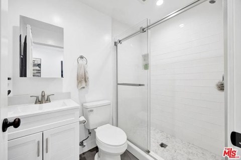 A white bathroom with a toilet, sink, and shower.