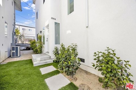 A white house with a green bush in front of it.