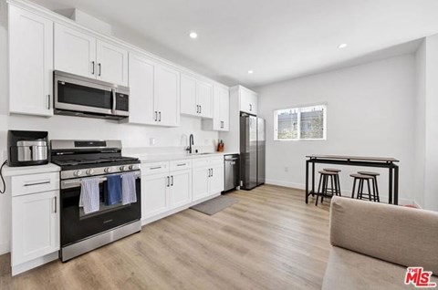 A kitchen with white cabinets and a black stove top oven.