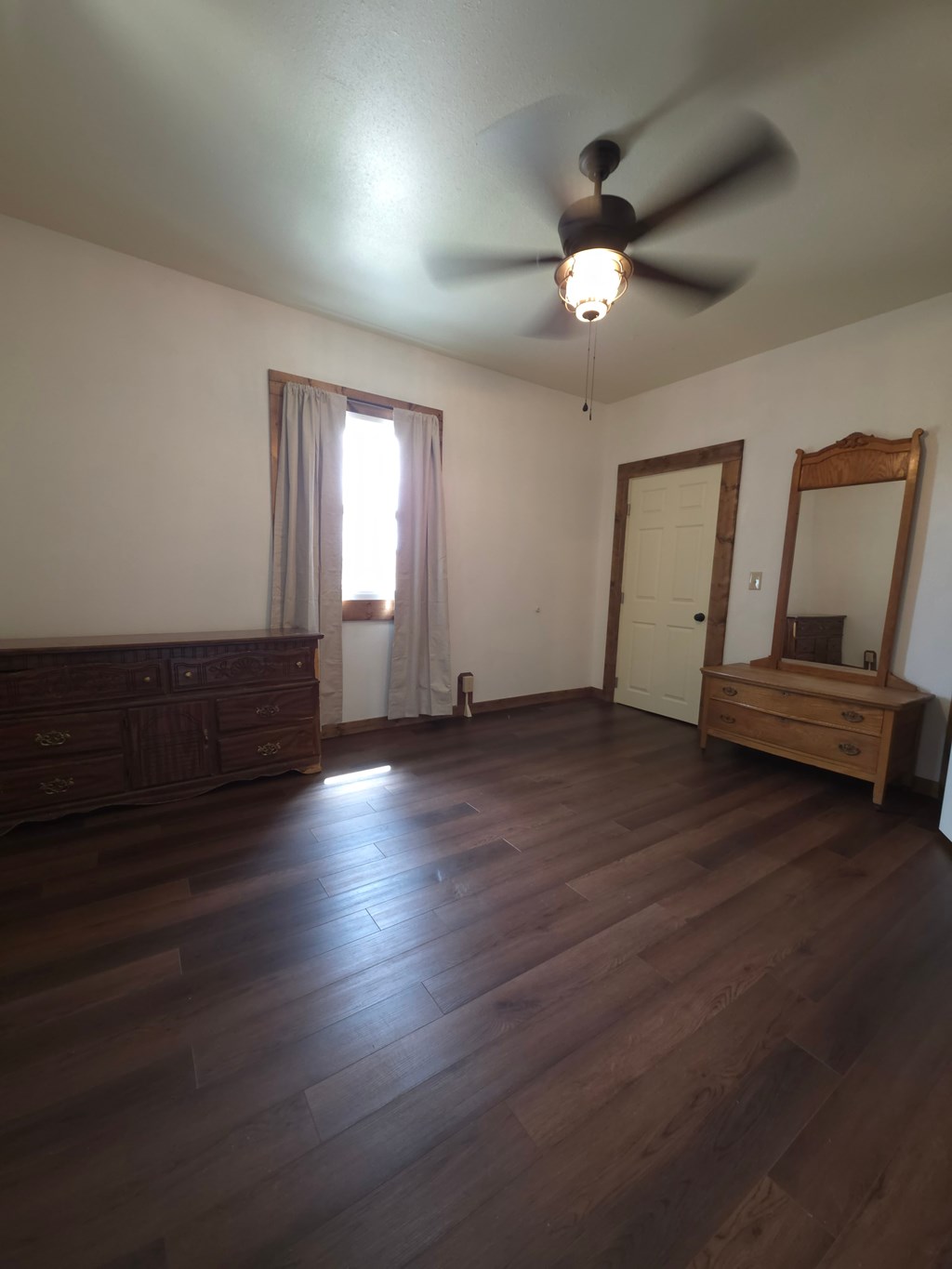 A room with a ceiling fan and wooden floors.