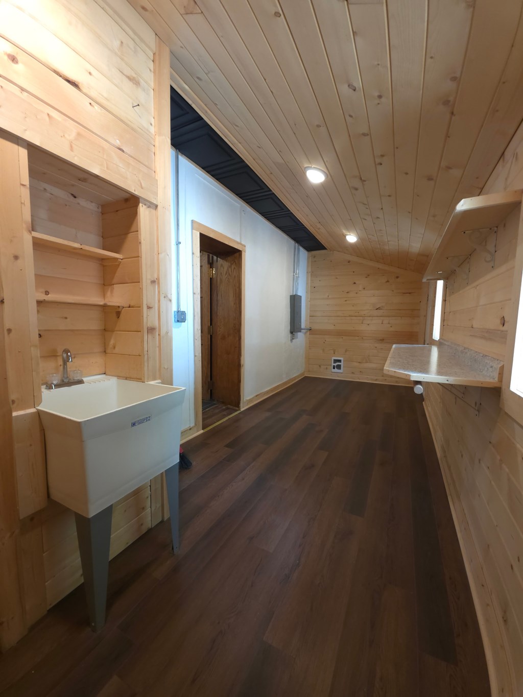A bathroom with wooden walls and floor and a white sink.