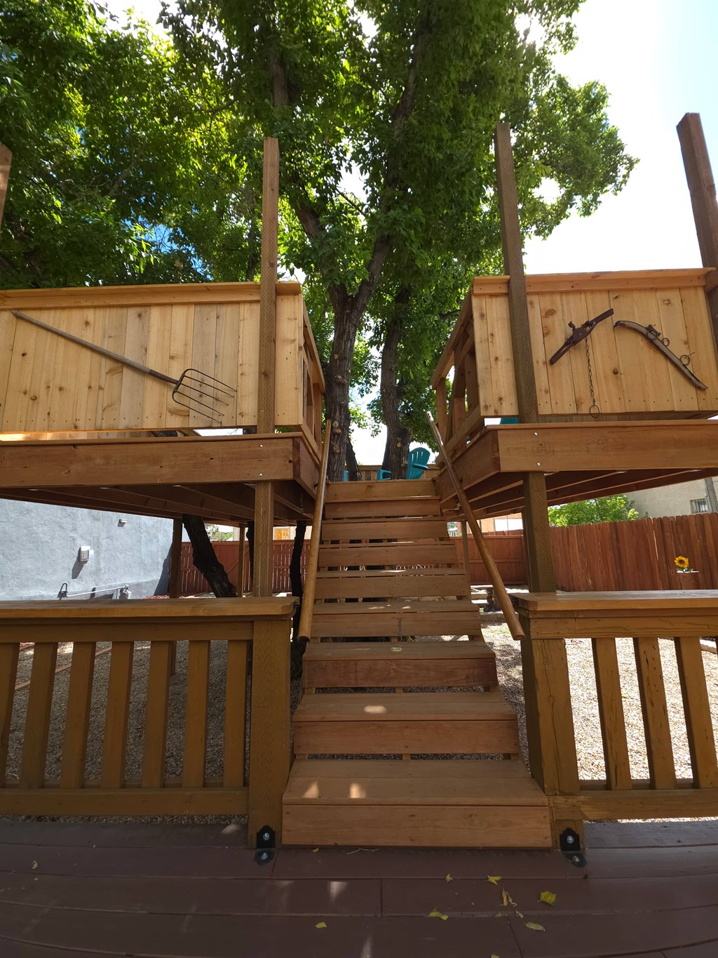A wooden staircase with a railing is in front of a tree.