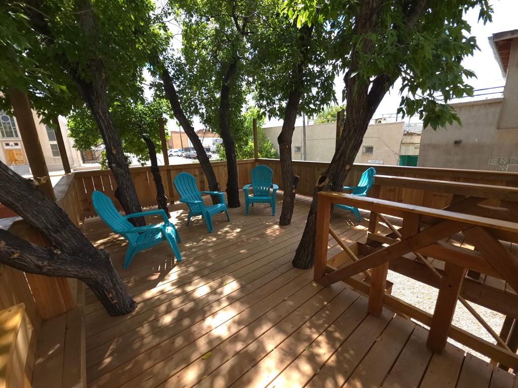 A wooden deck with blue chairs and trees.