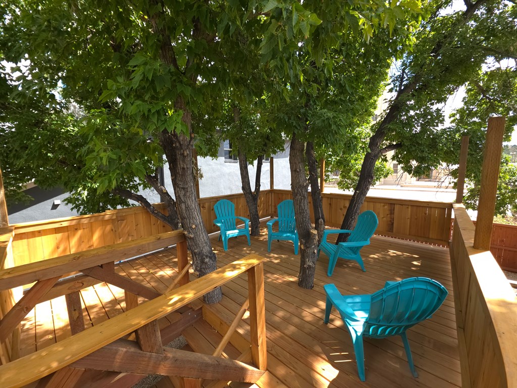 A wooden deck with blue chairs and a table.