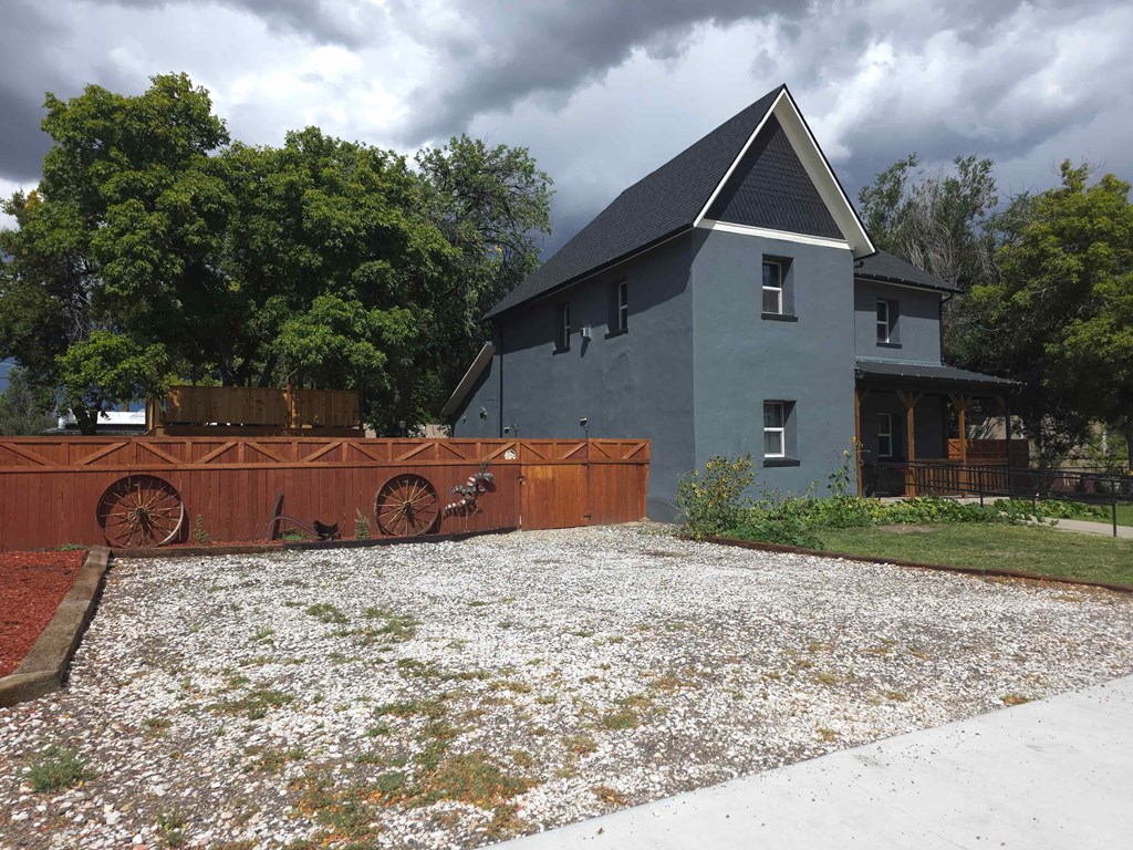 A grey house with a wooden fence and a field of white flowers in front.