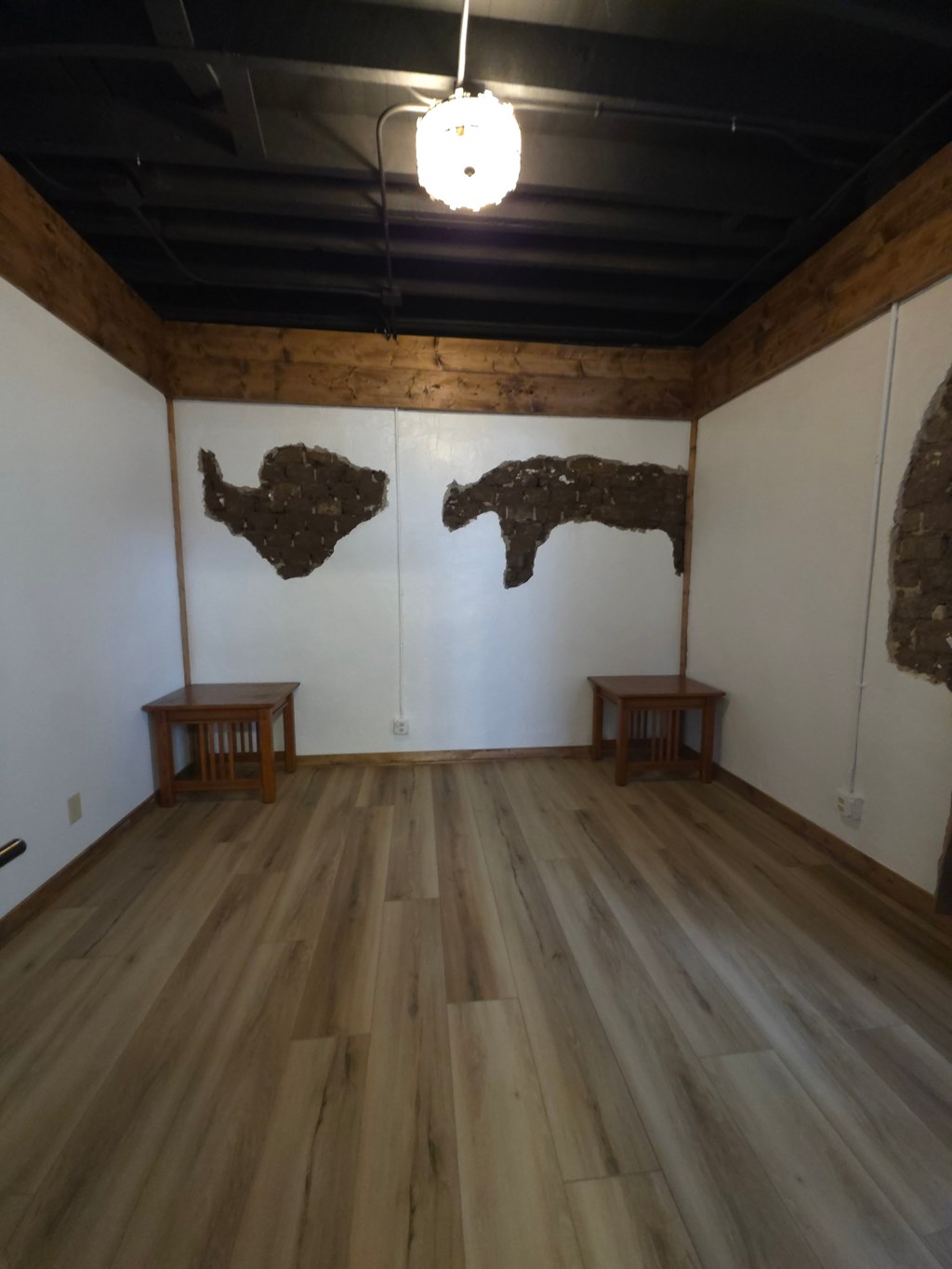 A room with wooden floors and a white wall with a wooden beam on top.