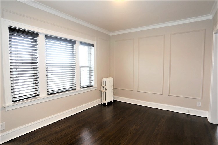 A room with wooden floors and a window with blinds.