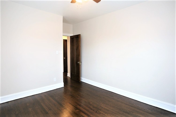 A room with a wooden floor and a brown door.
