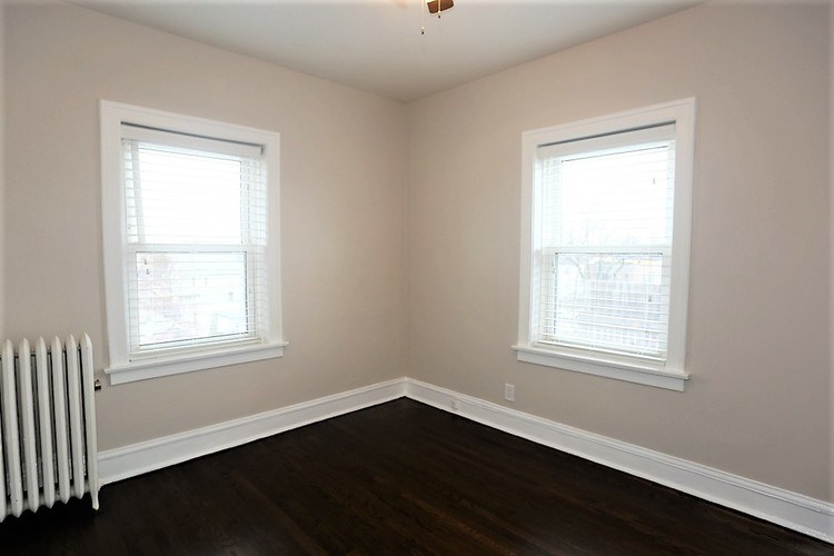 A room with two windows and a radiator on the wall.