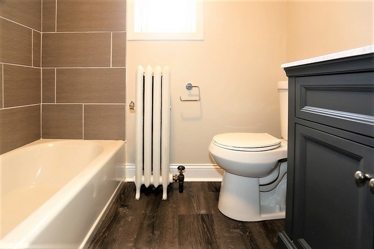 A white toilet sits next to a white bathtub in a bathroom.