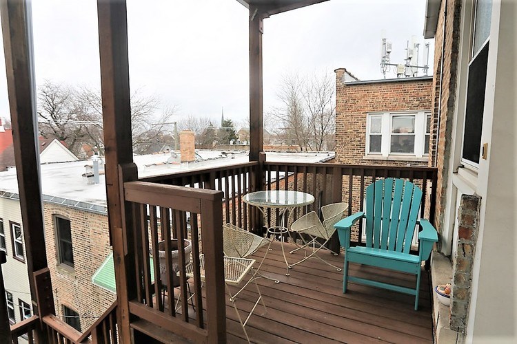 A balcony with a blue chair and a table.