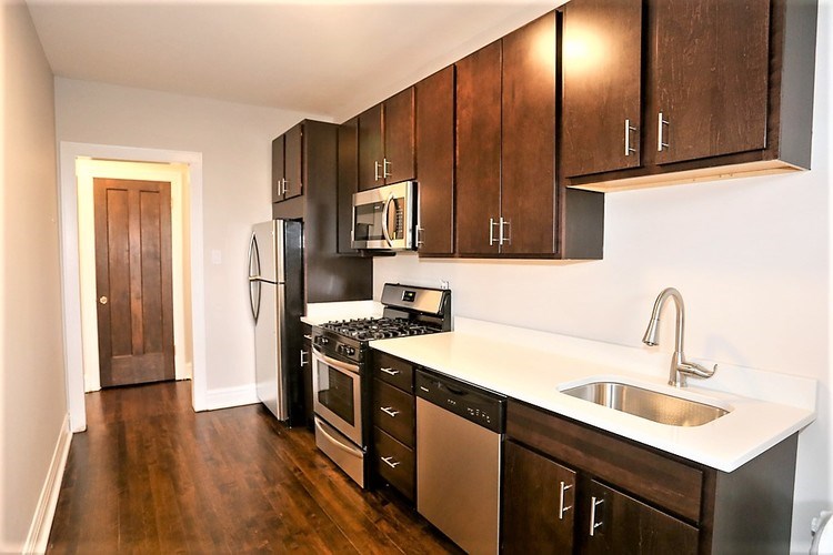 A kitchen with dark wood cabinets and stainless steel appliances.