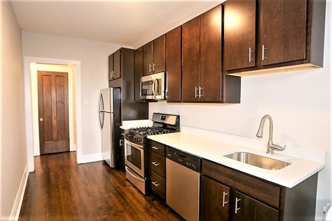 A kitchen with dark wood cabinets and stainless steel appliances.