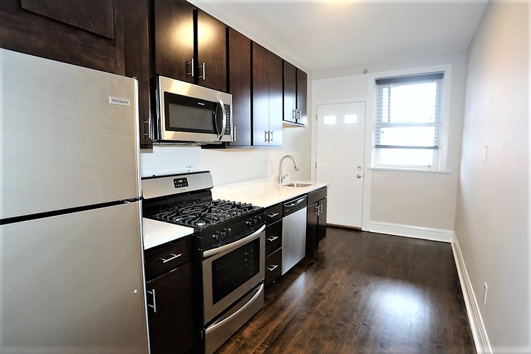A kitchen with white appliances and dark wood cabinets.