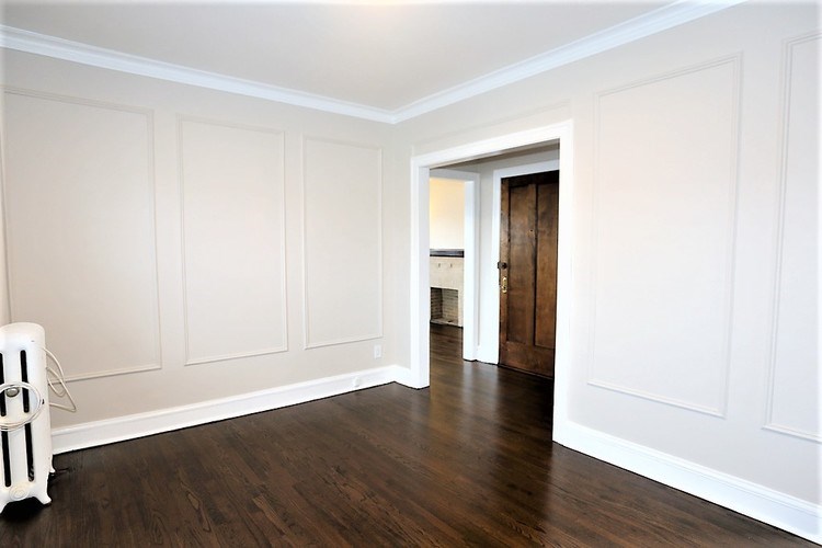 A white room with wood floors and a white radiator.