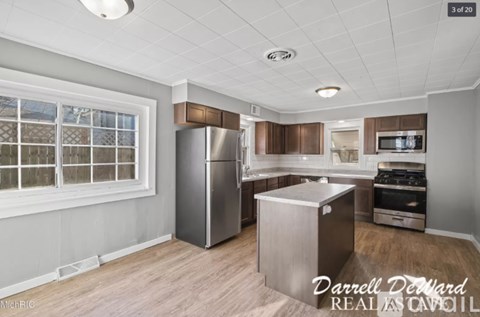 A modern kitchen with stainless steel appliances and wooden flooring.