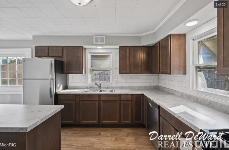 A kitchen with brown cabinets and a marble countertop.