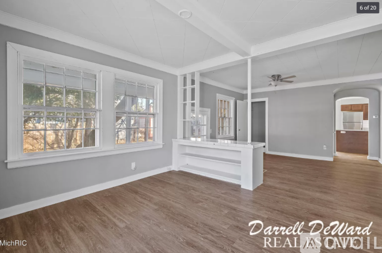 A spacious room with wood flooring and a ceiling fan.