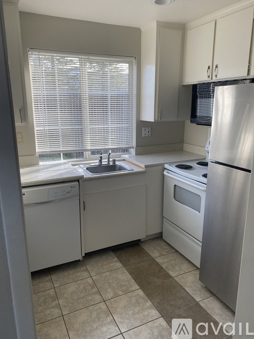 A kitchen with a stove, sink, and refrigerator.