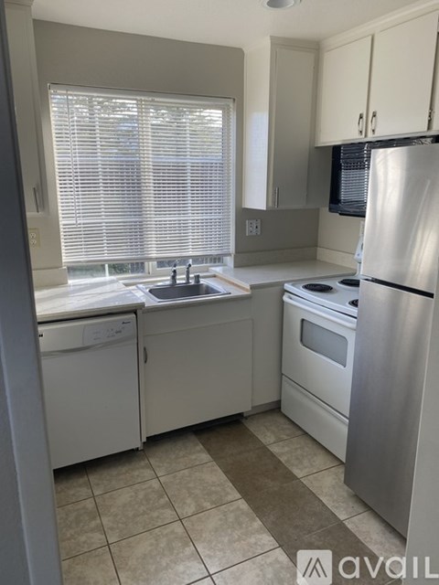 A kitchen with a stove, sink, and refrigerator.