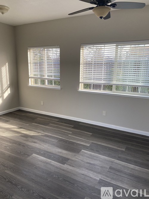A room with a ceiling fan and two windows with blinds.