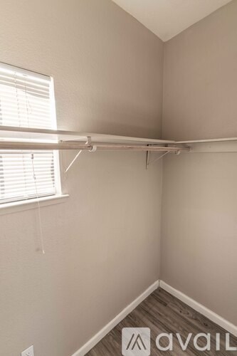 A room with a white wall and a window with blinds.