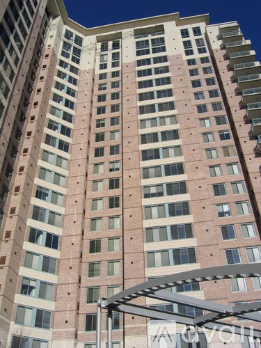 A tall building with a lot of windows and a metal structure in front of it.
