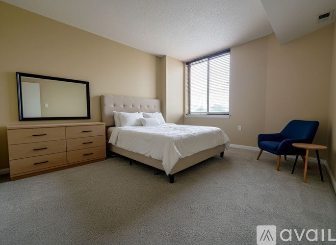 A spacious room with carpeted floor and beige walls, with a doorway leading to another room.