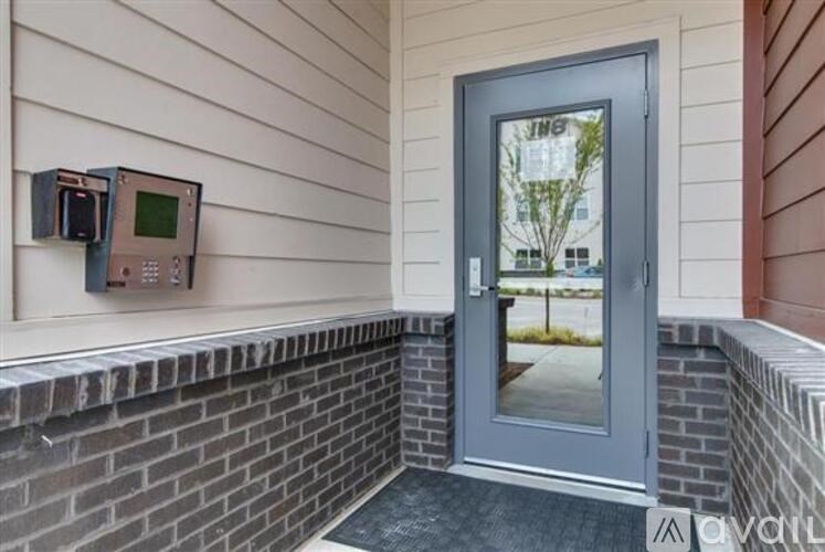 A grey door with a window on the right side and a brick wall below it.