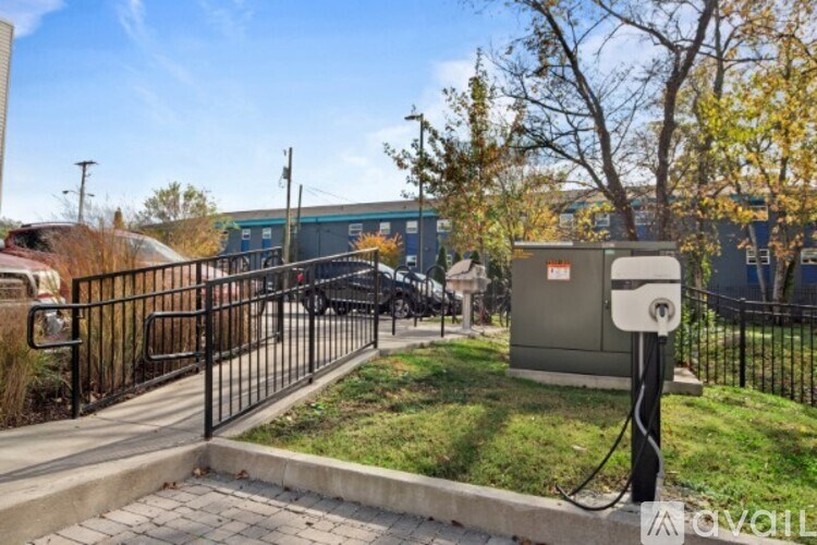 A black metal fence surrounds a grassy area with a utility box on a pole.