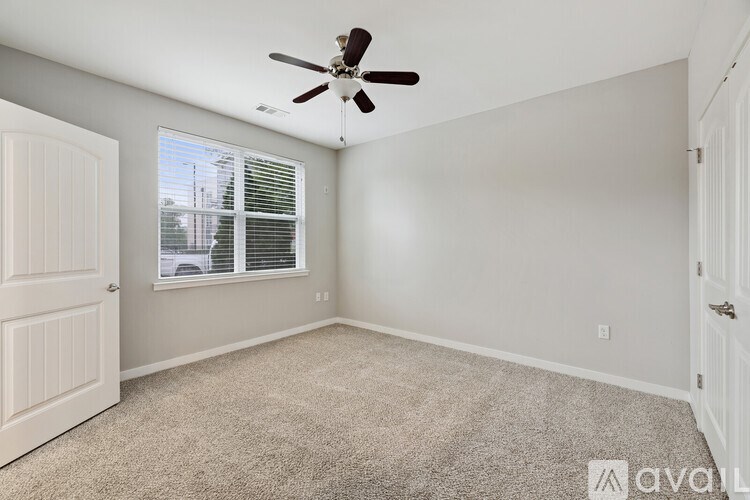 A room with a ceiling fan and car window view.